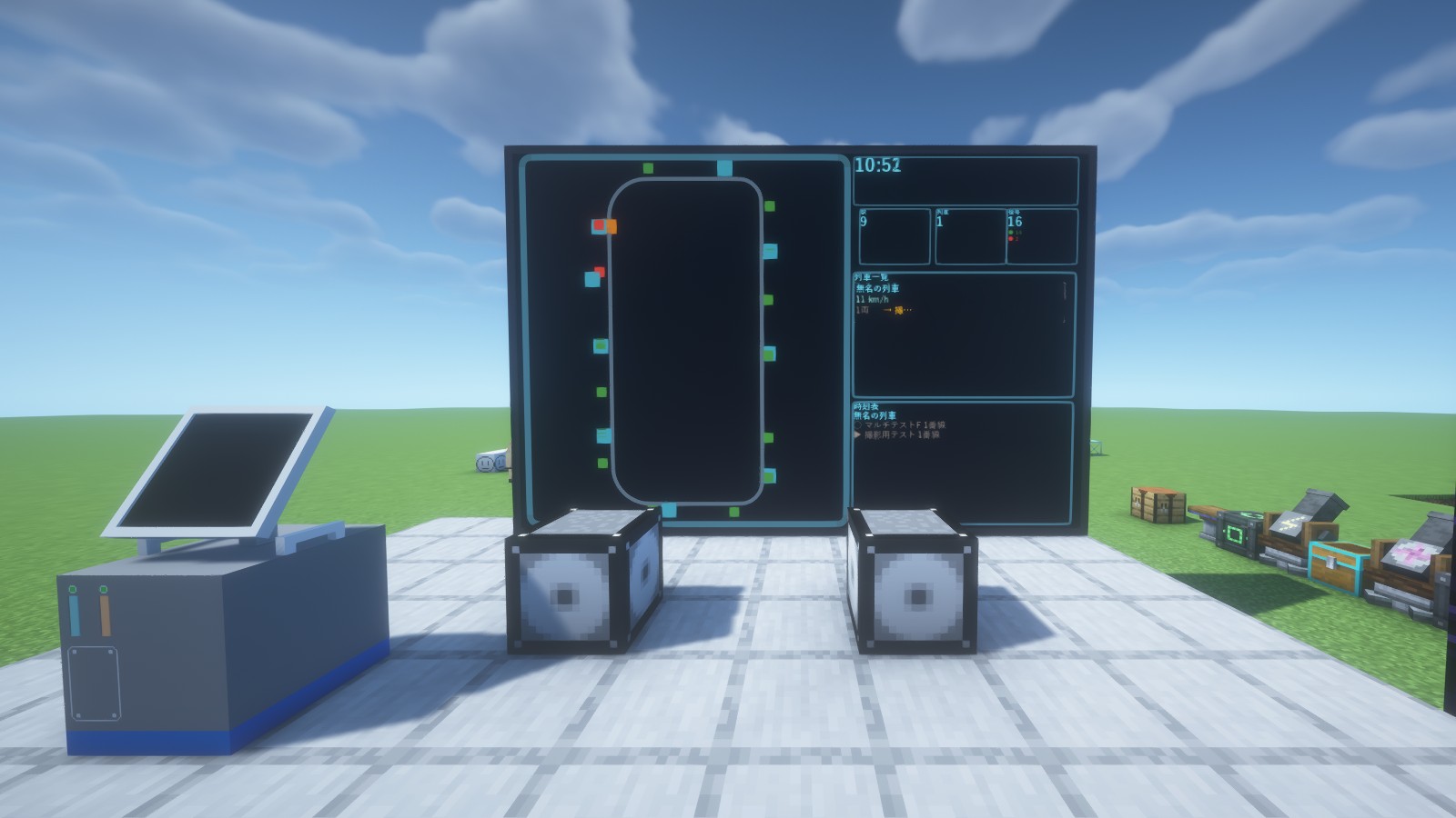 A wall-sized monitor standing in the plaza in front of a station. On the left, a loop route map with its stations; on the right, the time, the number of stations, trains and signals, a train list and a timetable. A speaker and a Management Computer in the foreground